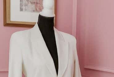 Mannequin wearing a white blazer in pink room