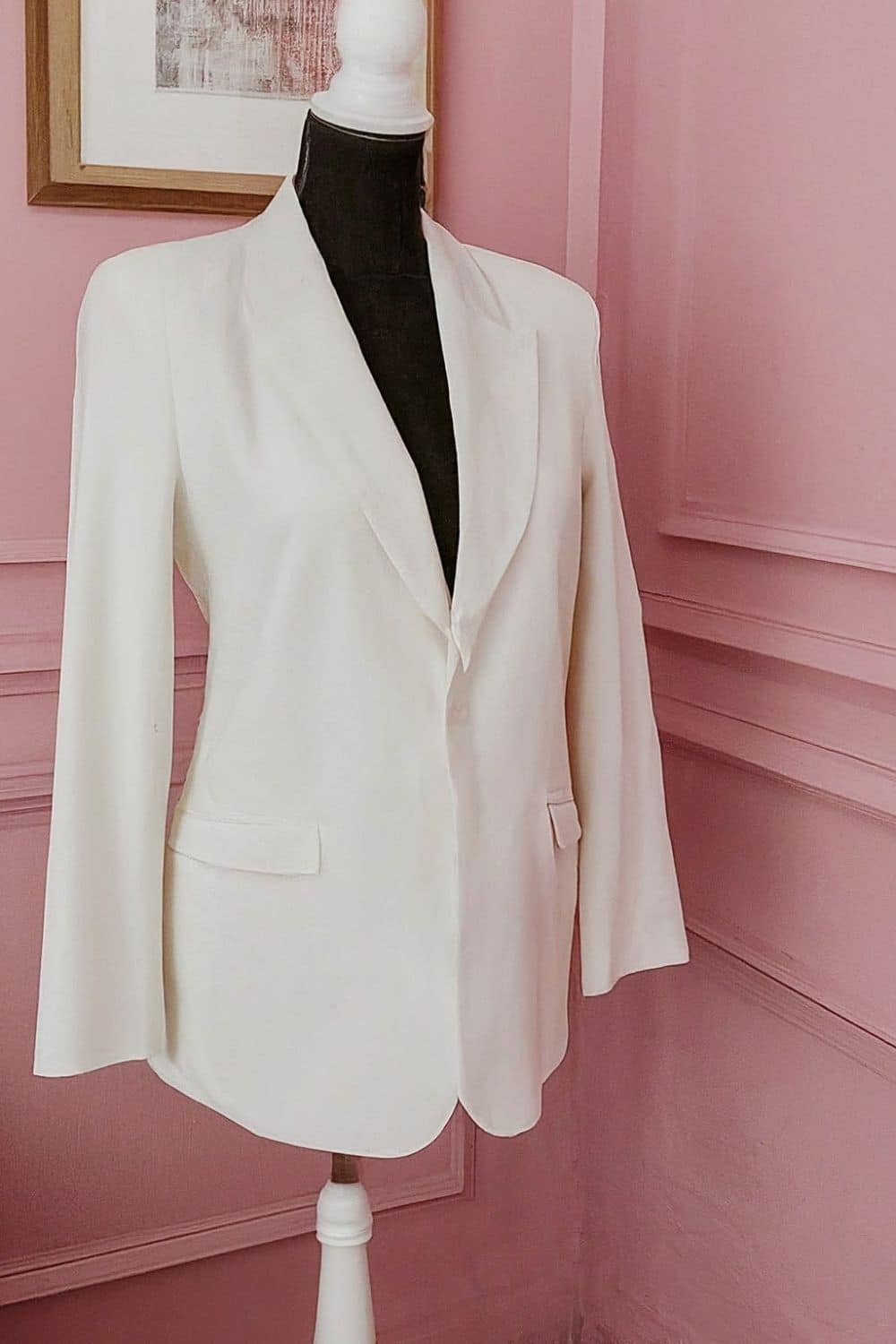 Mannequin wearing a white blazer in pink room