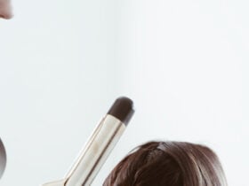 woman curling curling brunette hair with curling iron